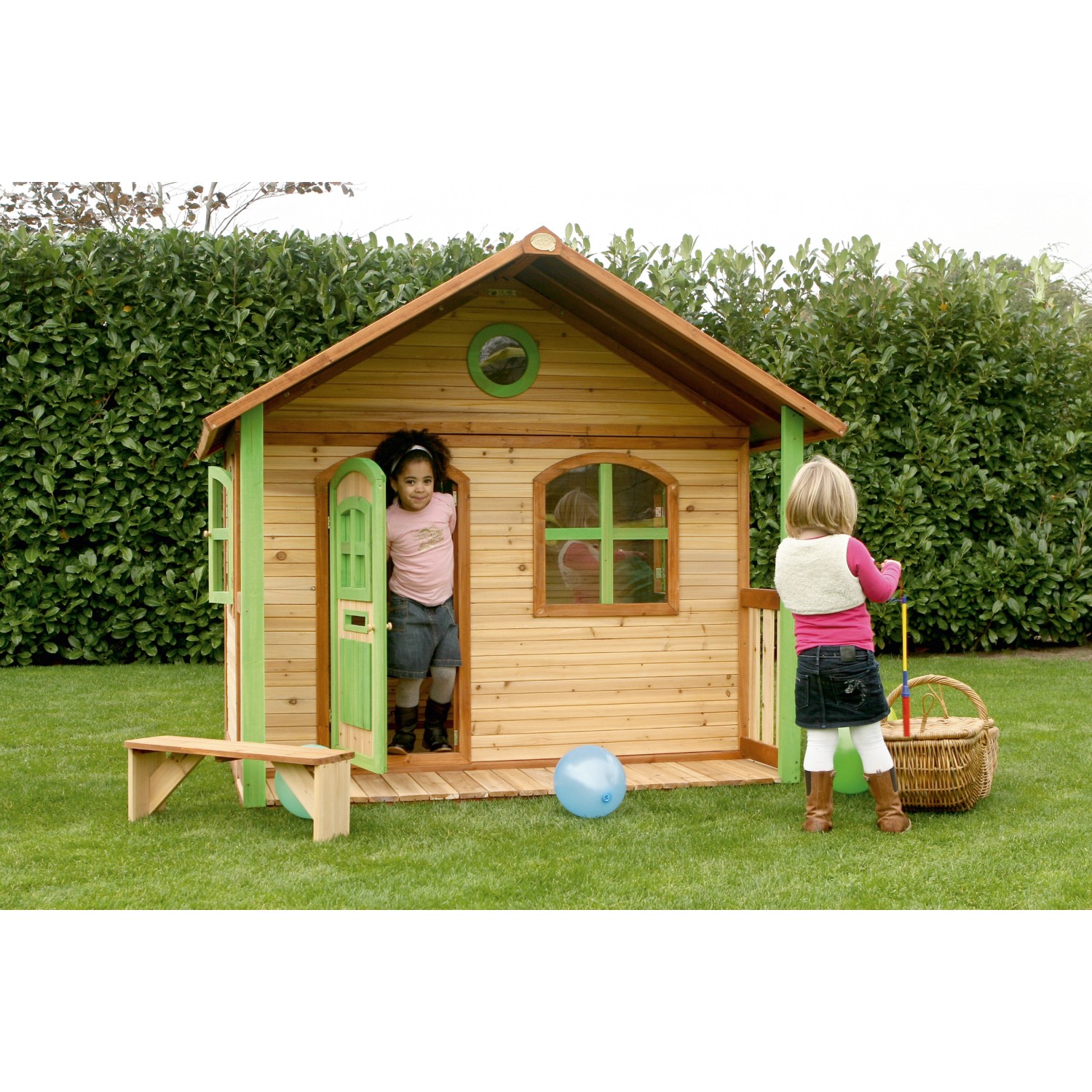 Axi Milan Spielhaus aus Holz in Braun und Grün mit zwei spielenden Kindern im Garten.