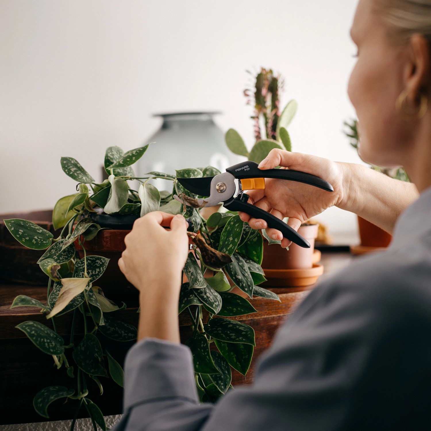 Frau schneidet Pflanze mit Fiskars Bypass-Gartenschere Solid P121. Astschere mit Antihaftbeschichtung.