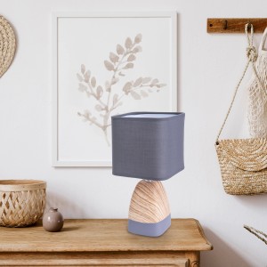 Näve Tischleuchte Cremona mit grauem Textilschirm auf Holztisch.