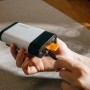 Hand lädt Fiskars 12V 4Ah Akku mit USB-C Kabel. Kompakte, weiß-schwarze Powerbank für Gartengeräte.