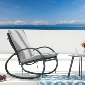 Hellgrauer Svita Eiby Deluxe Schaukelstuhl mit Armlehnen und Polsterung auf Terrasse am Meer.