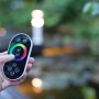 Heissner RGB-Controller für Teichbeleuchtung mit Farbrad-Fernbedienung in der Hand.