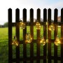 Globo LED-Solarlichterkette mit 10 warmweißen Birnen an einem Holzzaun im Garten.