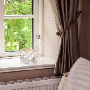 Fünf transparente Glas-Dekoflaschen mit Muscheln und Holzkorken, als maritimes Deko-Set auf einer Fensterbank platziert.