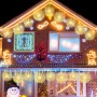 Zwei goldene LED-Leuchtkugeln in Pusteblumen-Optik als Weihnachtsdekoration hängen an einem Haus.