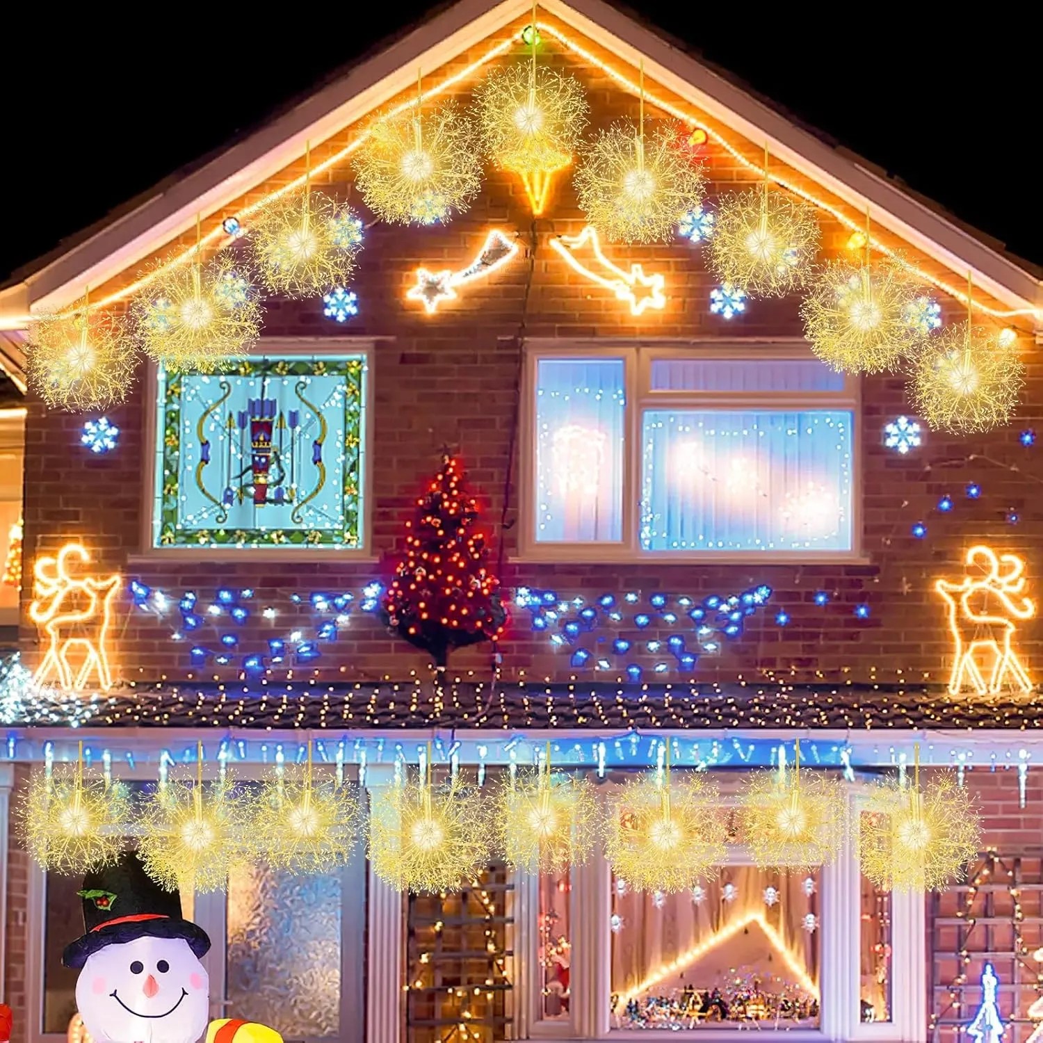 Zwei goldene LED-Leuchtkugeln in Pusteblumen-Optik als Weihnachtsdekoration hängen an einem Haus.
