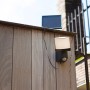 Anthrazitfarbene Lutec LED Solar-Wandleuchte Sunshine mit Bewegungssensor an Holzwand.