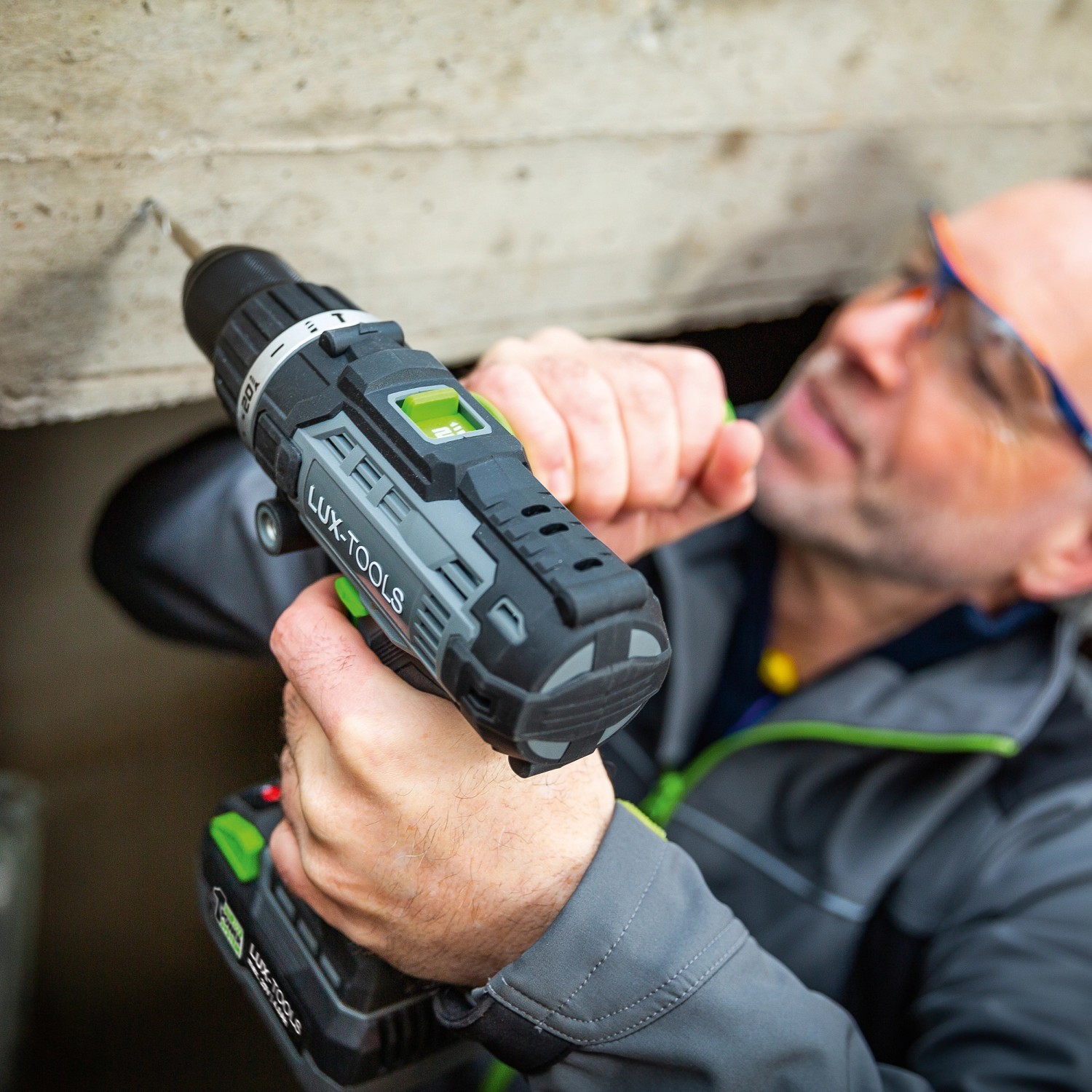 LUX Akku-Schlagbohrschrauber A-BS-20/S beim Bohren in Betonwand, Teilansicht Mann mit Schutzbrille.