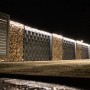 LyghtUp LED-Zaunbeleuchtung Set in Silber an einem Zaun mit Gabionen und einem Tor.