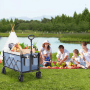 Blauer Sekey Faltbollerwagen mit Picknick-Inhalt am Seeufer, Familie picknickt. Ideal für Camping & Transport.
