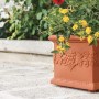 Quadratischer, terrakottafarbener Blumentopf Venedig mit mediterranem Dekor und gelben Blumen.