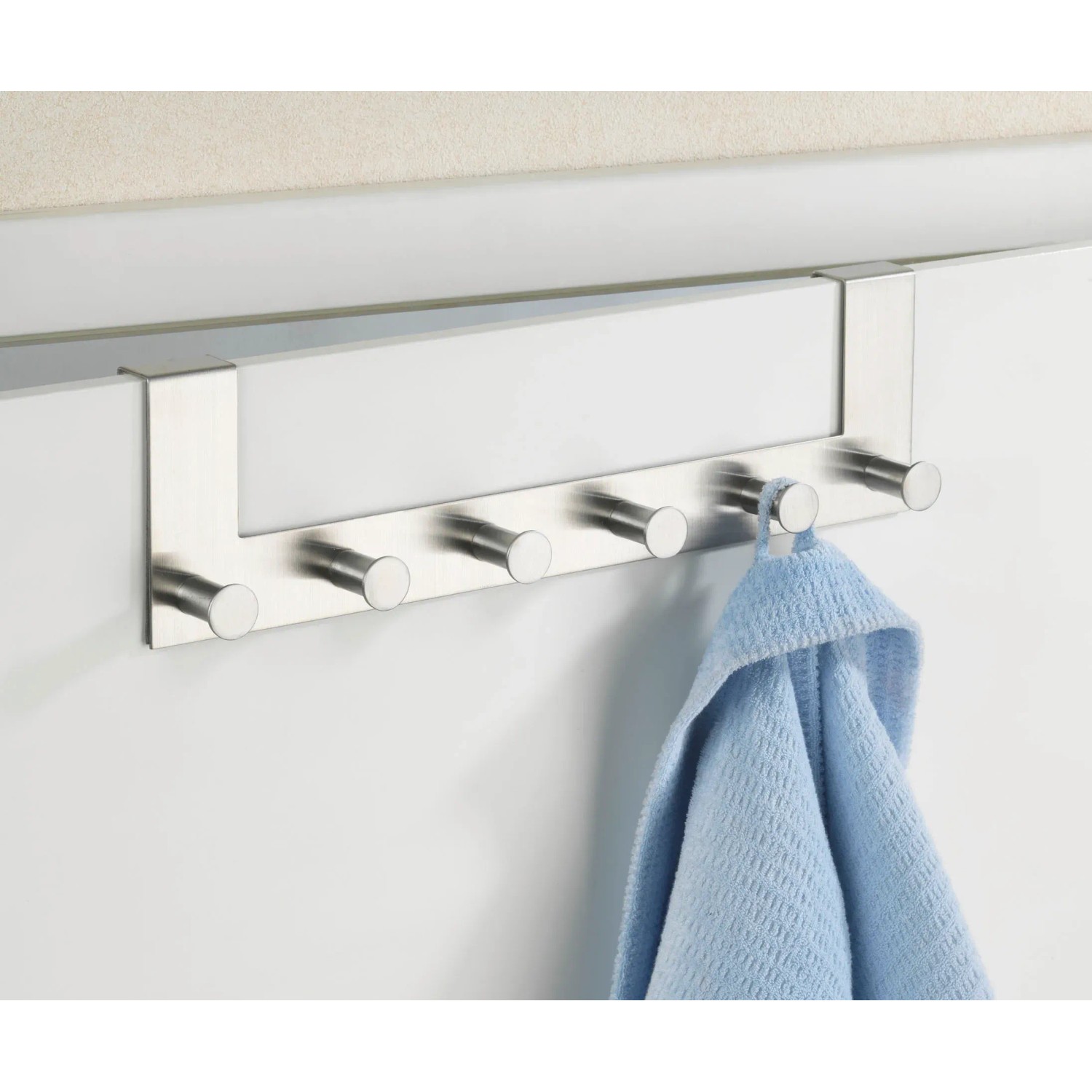 Wenko Türgarderobe Celano mit 6 Haken aus rostfreiem Edelstahl, an Tür mit blauem Handtuch.