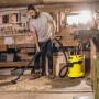 Mann saugt mit gelbem Kärcher WD 3 P Nass-Trockensauger Späne in Werkstatt.