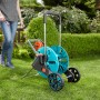 Gardena CleverRoll M Easy Schlauchwagen mit Frau im Garten. Schlauchwagen ist blau/grau und hat Räder.