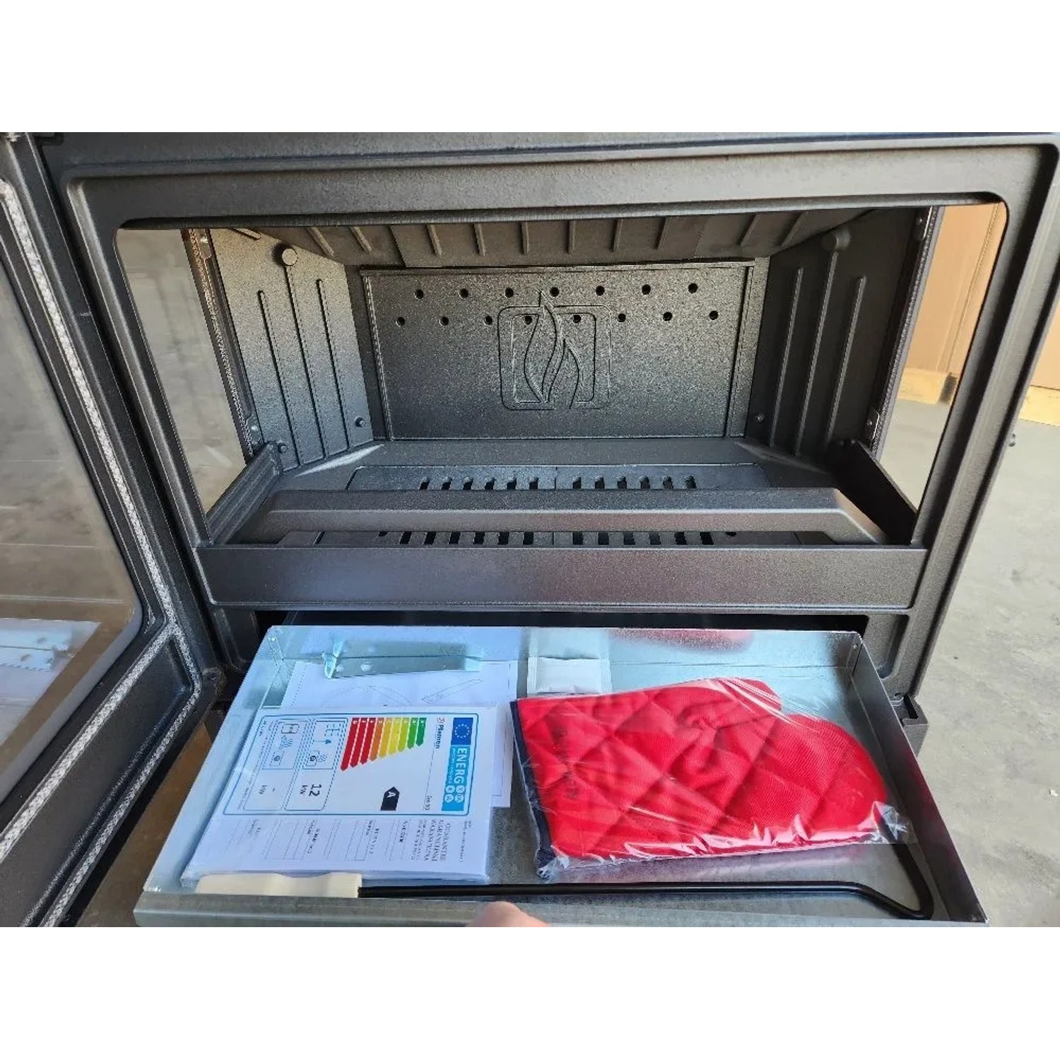 Innenansicht Plamen Gusskaminofen ECO 50, 12 kW mit Zubehör im Aschekasten.