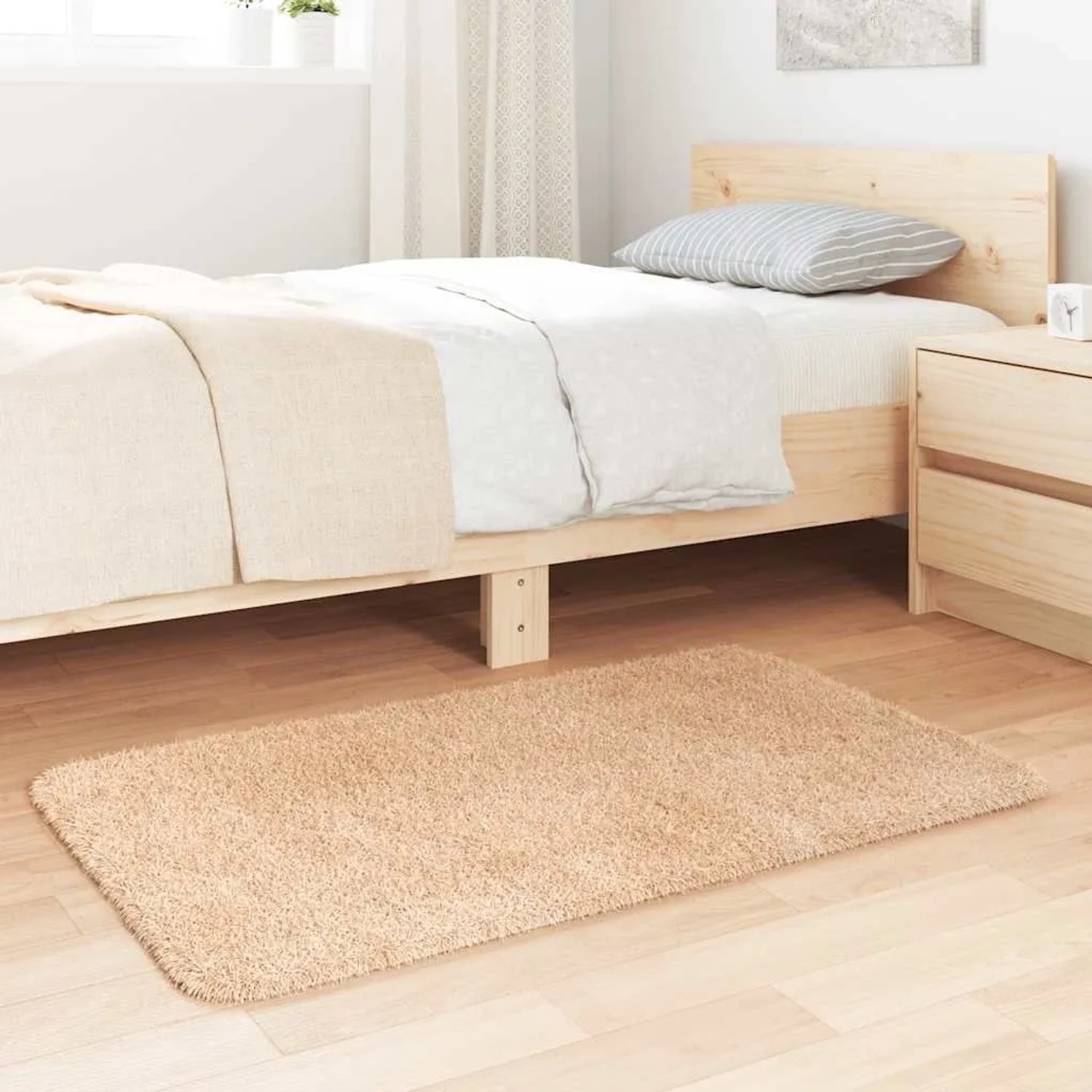 Beiger Shaggy Hochflorteppich aus Polyester, 60x100 cm, im Schlafzimmer auf Holzfußboden.