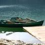 Zwei grüne Boote mit Rudern am See, behandelt mit Contura Bootslack.