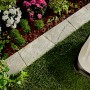 KANN Rasenkante Nativa Kalkstein (35x20x4 cm) mit Mähroboter im Garten.
