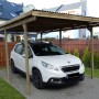 Holz-Carport mit Flachdach (300x495cm) und geparktem, weißen Auto.