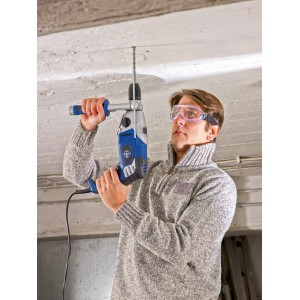 Mann bohrt mit Schlagbohrmaschine und LUX Schutzbrille mit Band in Decke.