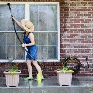 Bronzefarbener Relaxdays Schlauchhalter aus Gusseisen an einer Ziegelwand mit Gartenschlauch.