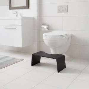 Schwarzer Bambus Toilettenhocker vor weißer Toilette im Bad. Fördert natürliche Hocksitzhaltung.