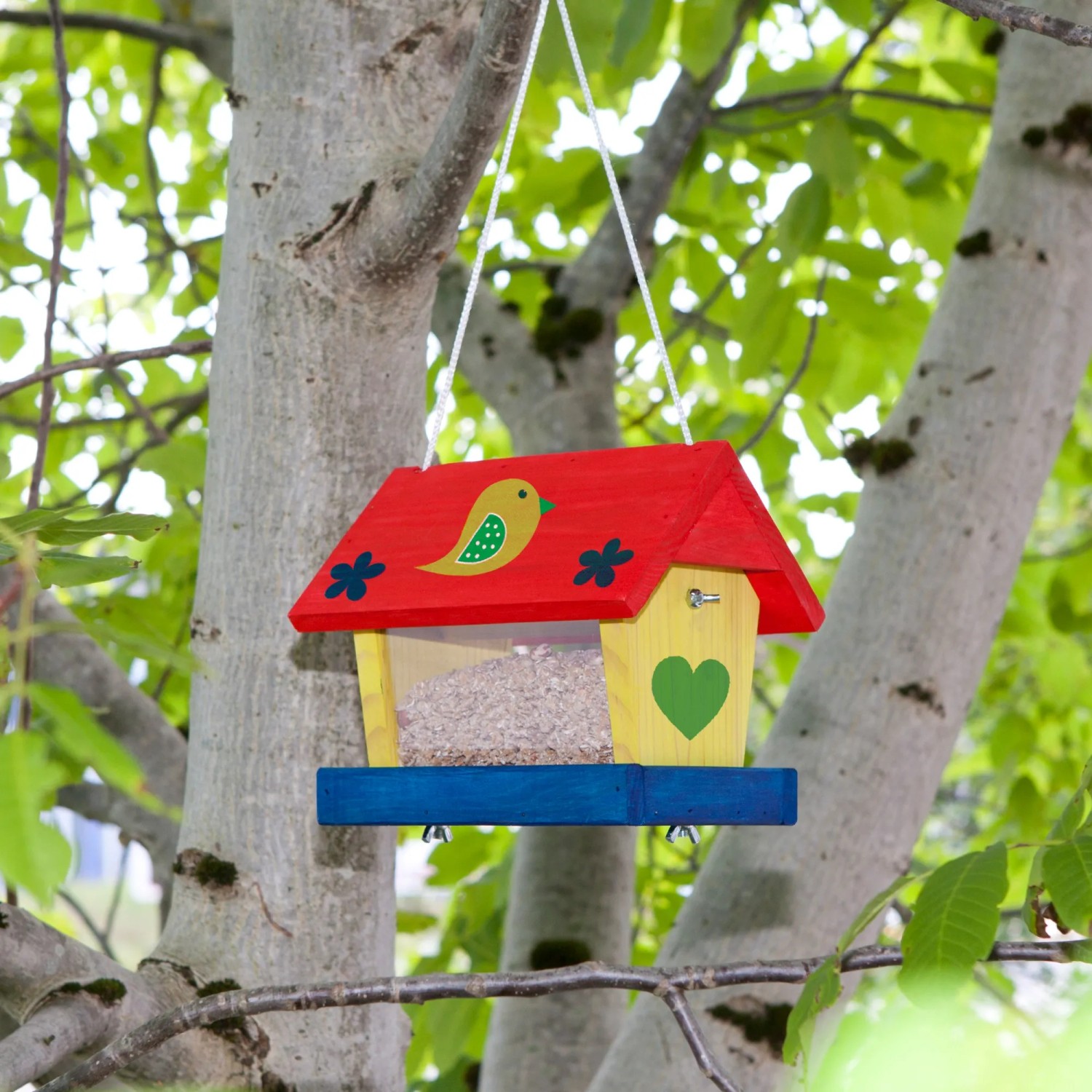 Bemaltes Windhager Vogelfuttersilo Woodpecker aus Holz, hängend im Baum.