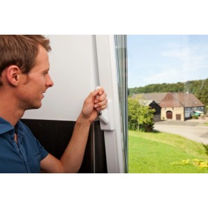 Mann bedient weißes Abus Fenstergriff-Schloss mit Alarm zur Fenstersicherung.