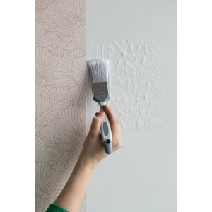 Hand streicht Tapetenkleister mit Pinsel auf Wand. Wallpro Werkzeug-Set für Vliestapeten.