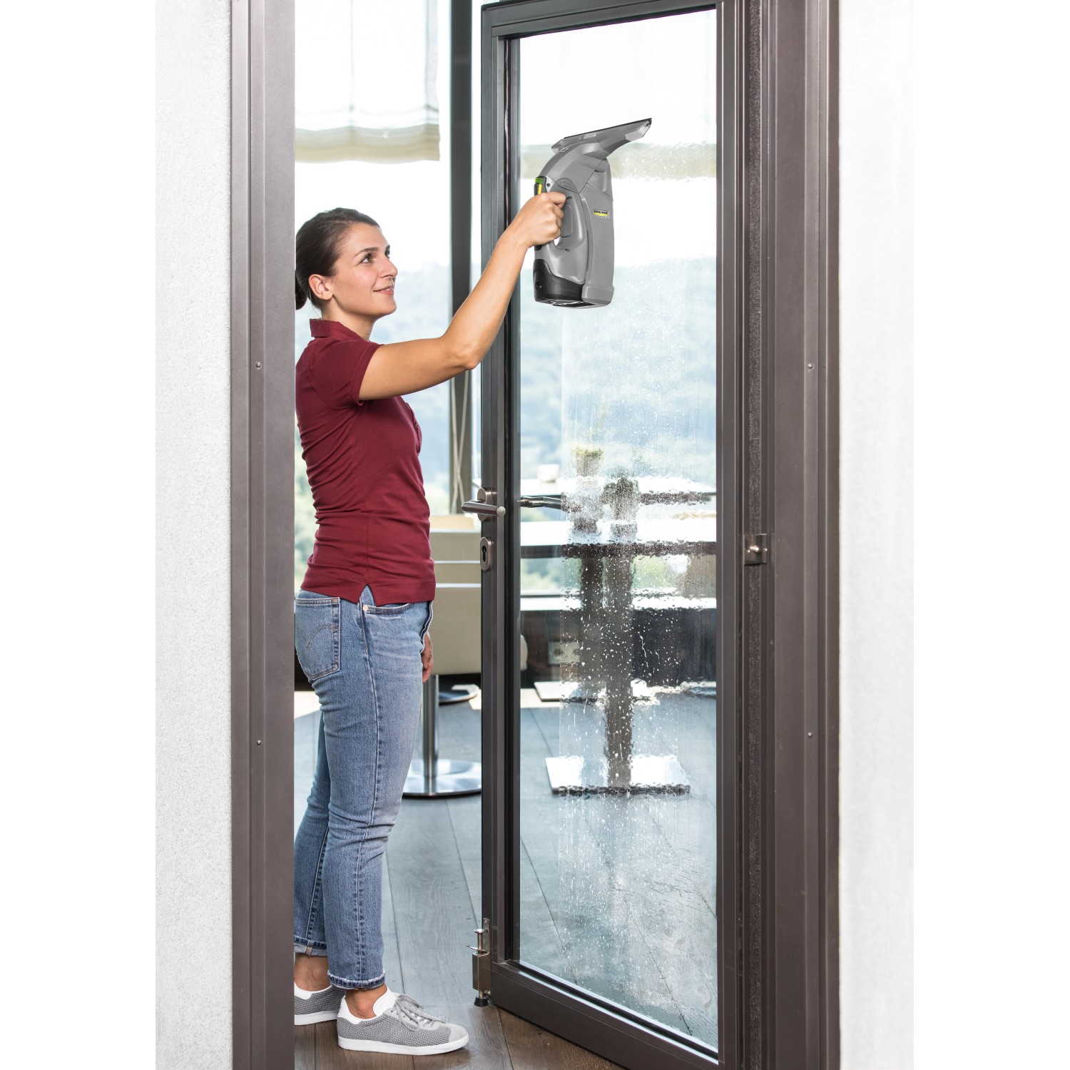 Frau reinigt Fenster mit Kärcher Fenstersauger WVP 10. Das Gerät sorgt für streifenfreie Sauberkeit.