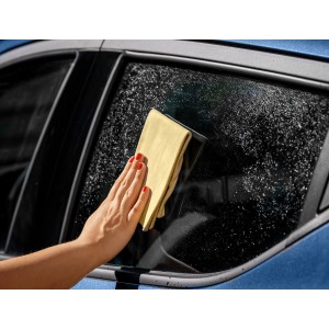 Frau reinigt Autoscheibe mit APA Fensterleder. Echtleder für streifenfreie Sauberkeit.