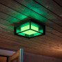 Quadratische Philips Hue Econic LED-Wandleuchte mit grüner Beleuchtung an einer Holzdecke.