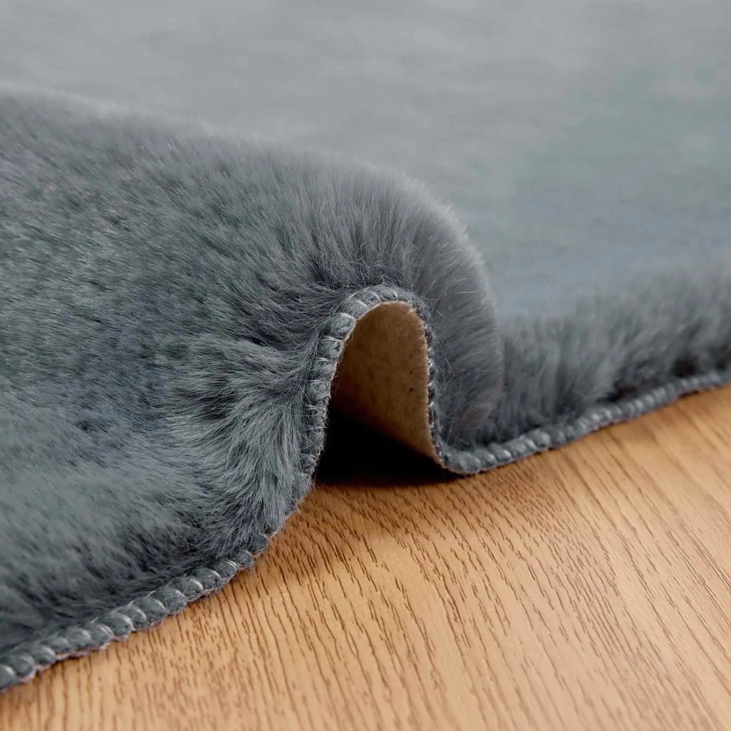 Anthrazitfarbener vidaXL Kunstfell Teppich Olite aus Polyester. Weiche, flauschige Oberfläche auf Holzfußboden.