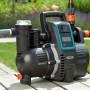 Gardena smart Haus- und Gartenautomat 5000/5 Set: Schwarze Gartenpumpe mit grauem Schlauch auf Holztisch.