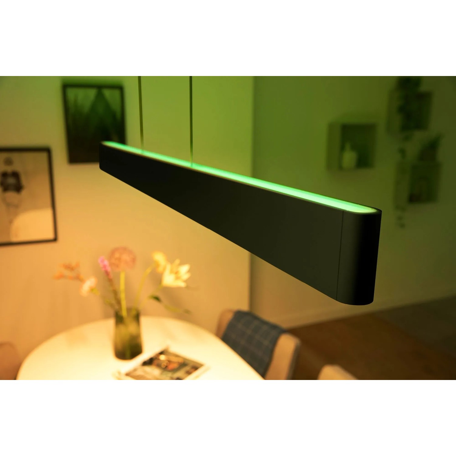 Schwarze Philips Hue Ensis LED Pendelleuchte mit Farbwechsel über Esstisch.