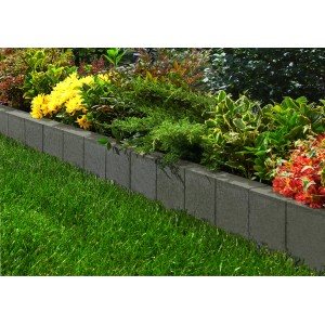 Anthrazitfarbener Rechteck Palisadenrandstein aus Beton als Beeteinfassung im Garten.