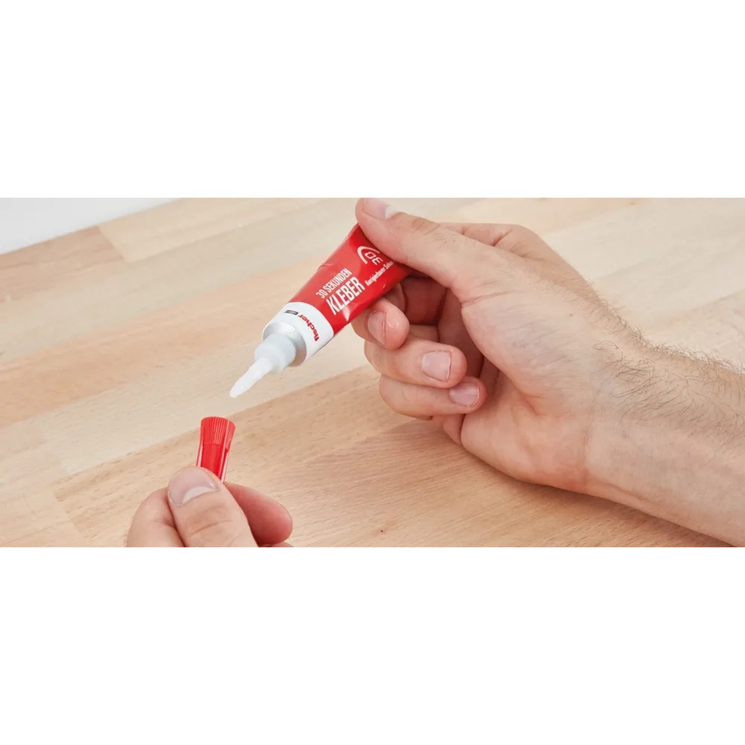 Hände öffnen Fischer 30 Sekunden Kleber (15g) Tube, roter Deckel wird entfernt.
