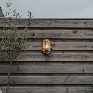 Goldene QAZQA Wandleuchte Noutica im maritimen Stil an Holzwand.