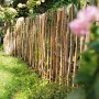 Natürlicher Staketenrollzaun aus unbehandelter Haselnuss im Garten.