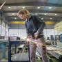 Frau schleift Metall mit dem Bosch Professional Winkelschleifer GWS 17-125 in einer Werkstatt.