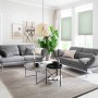 Helle Wohnraum-Szene mit grauen Sofas und grünem Schöner Wohnen Plissee Milla (90x130 cm) am Fenster.