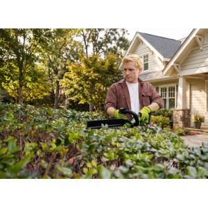 Mann in grünen Handschuhen trimmt Hecke mit Greenworks Akku-Heckenschere 51 cm Klinge. Präzise Gartenpflege.