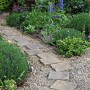 Gartenweg mit Buntkies Rhein (20-40mm) als Zierkies zwischen Steinplatten.
