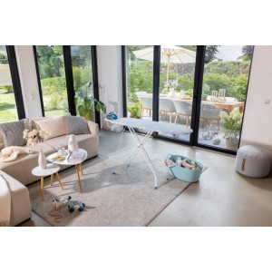 Leifheit Bügeltisch Classic M Basic Plus im Wohnzimmer. Weißes Bügelbrett mit Ablage, Steckdose & Kabelhalterung.