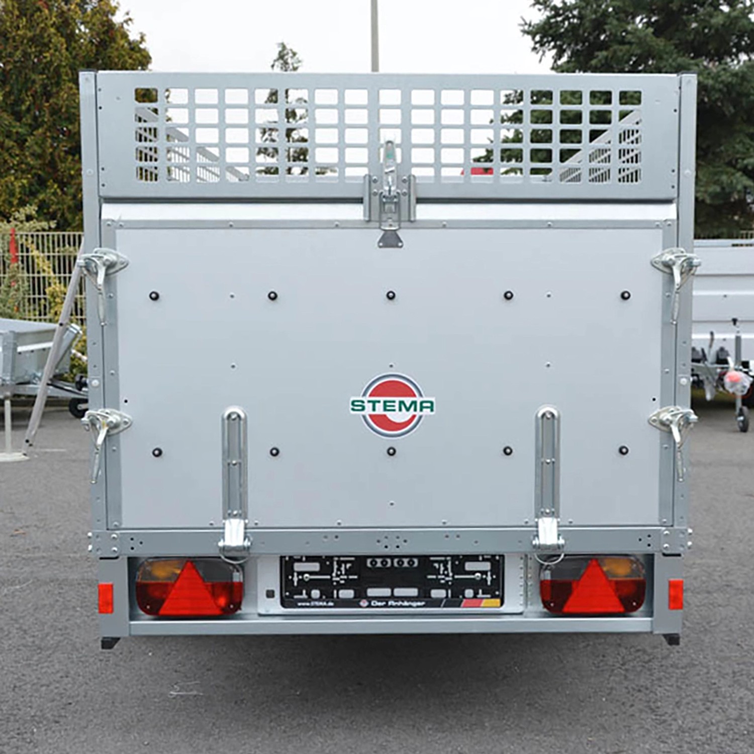 Stema REX 25 Kippanhänger mit Gitteraufsatz, Heckansicht mit Rückleuchten und Stema Logo.