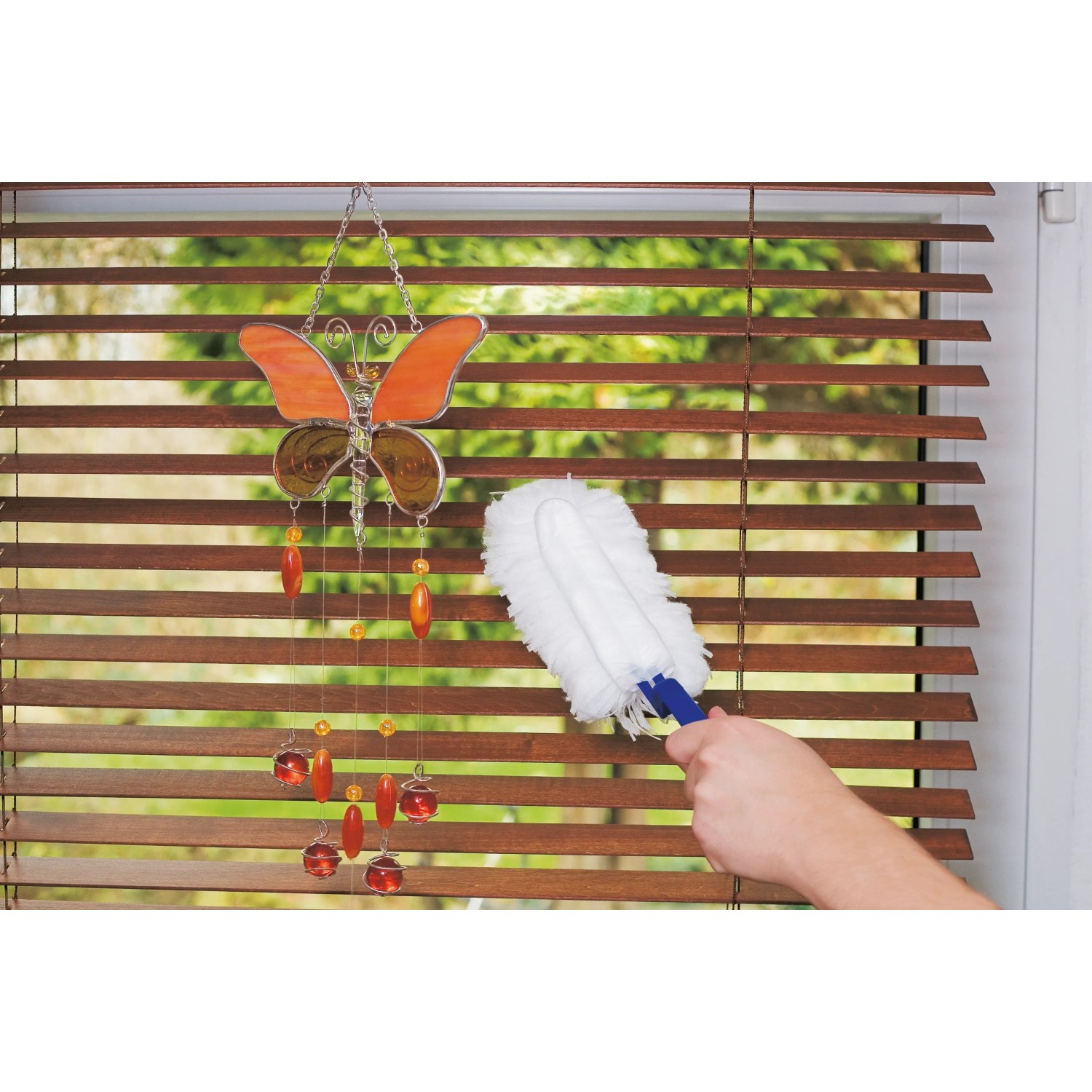 Staubfanggerät Mikrofaser im Einsatz vor Fensterjalousie und Deko-Schmetterling.