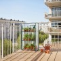 Grünes Balkongewächshaus aus Stahl mit transparenter PVC-Folie, aufgerollter Tür und 3 Etagen voller Pflanzen auf Holz-Balkon.