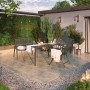 Gartenszene mit Sacramento Stapelstühlen aus Stahlgeflecht und passendem Tisch auf einer Terrasse.
