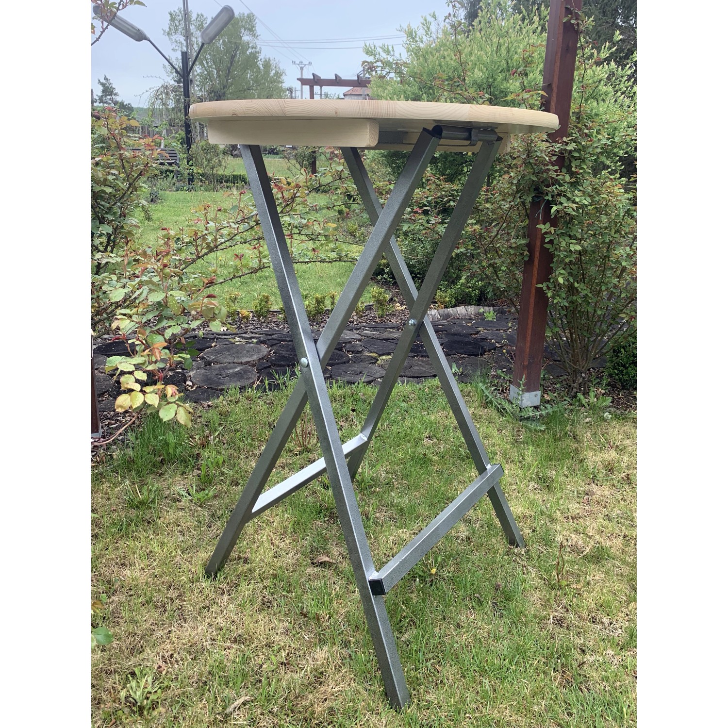 Klappbarer Stehtisch aus Holz und Metall für Garten und Terrasse.