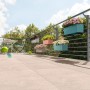 Mehrere bepflanzte Lechuza Balconera Blumenkästen in verschiedenen Farben am Balkongeländer.